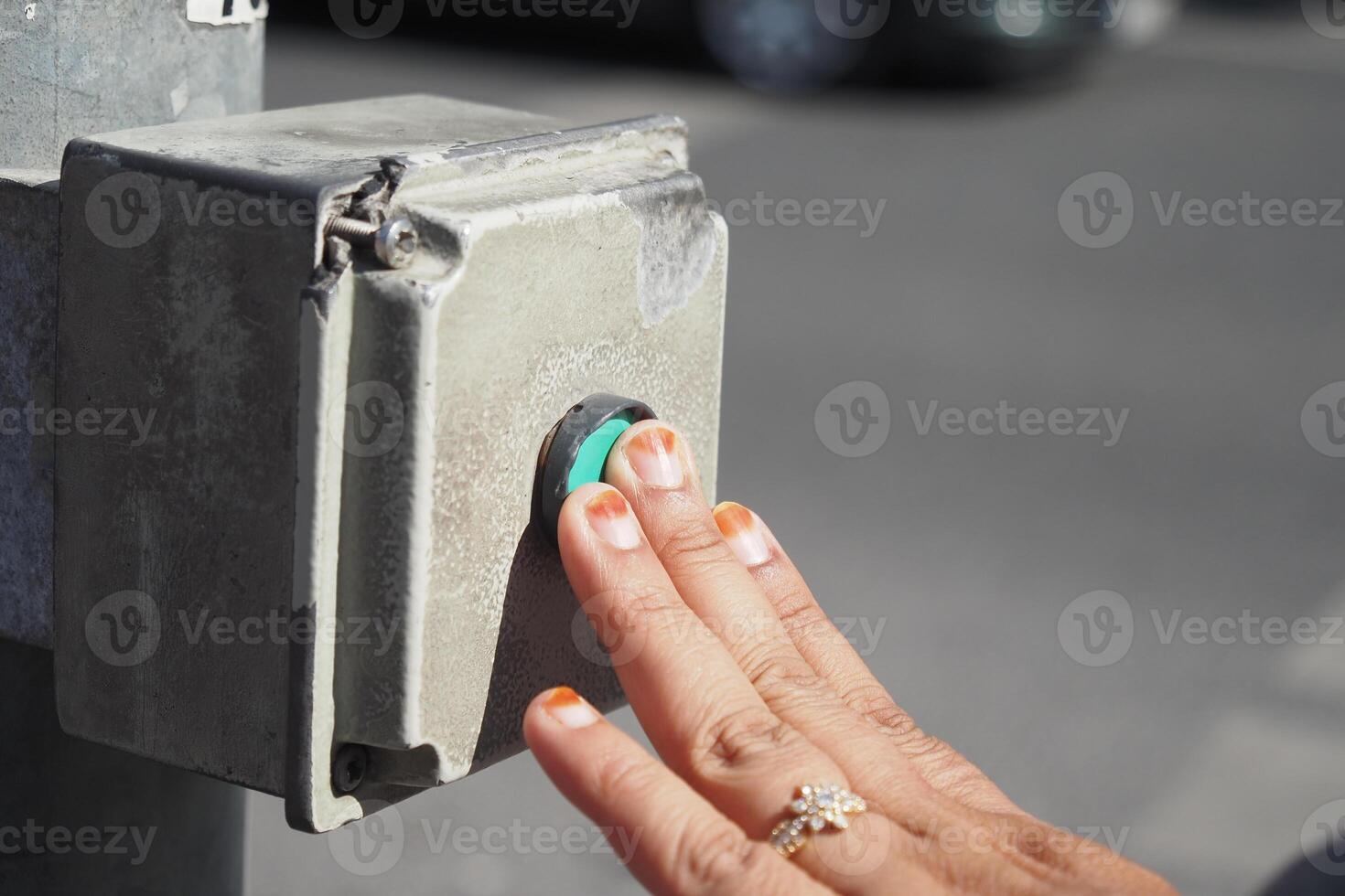 Hand pressing pedestrian crossing button in urban setting photo