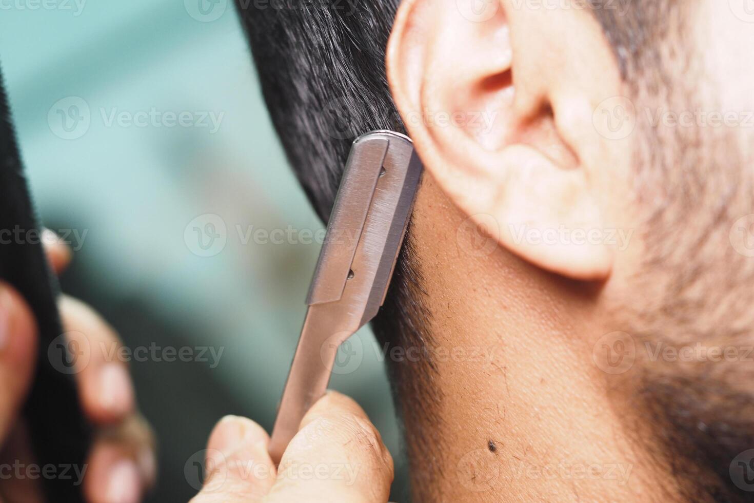 Close haircut is being given with a straight razor at a barber shop photo