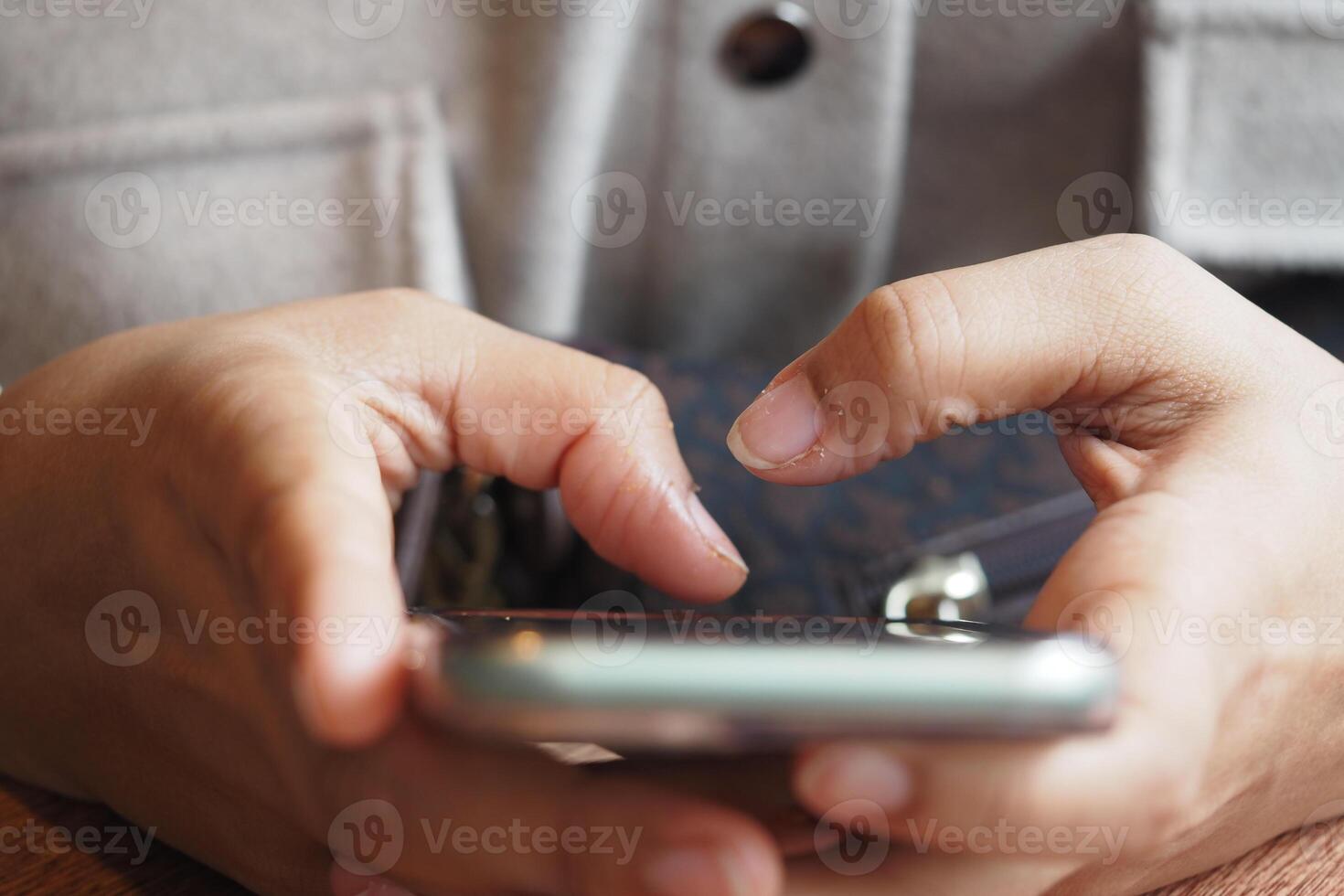 Person using smartphone while sitting at wooden table photo