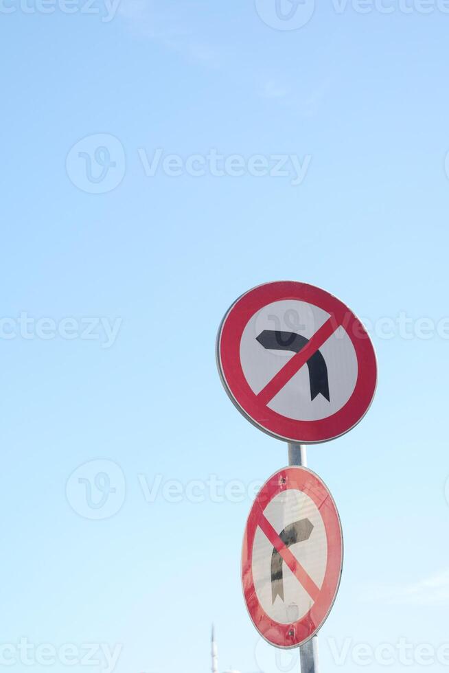 No U turn signs against a clear blue sky in a traffic area photo