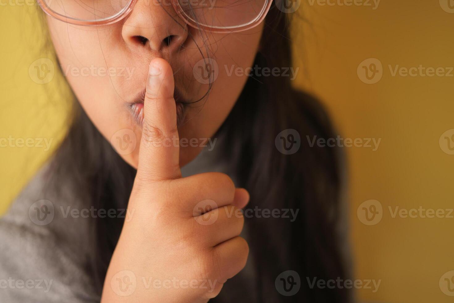 Girl making a shushing gesture with a playful expression indoors photo