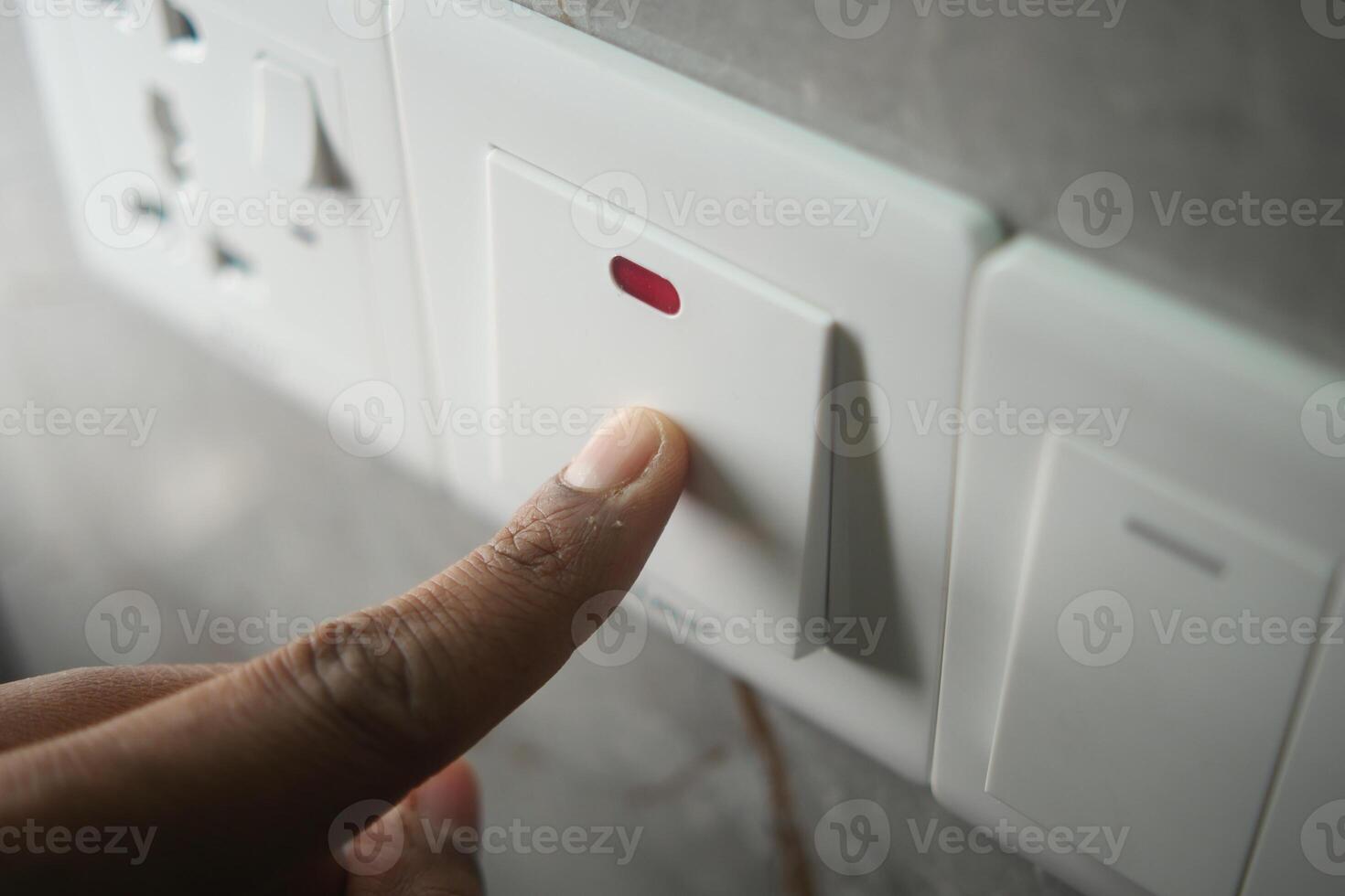 Person pressing a switch for electrical control in a home setting photo