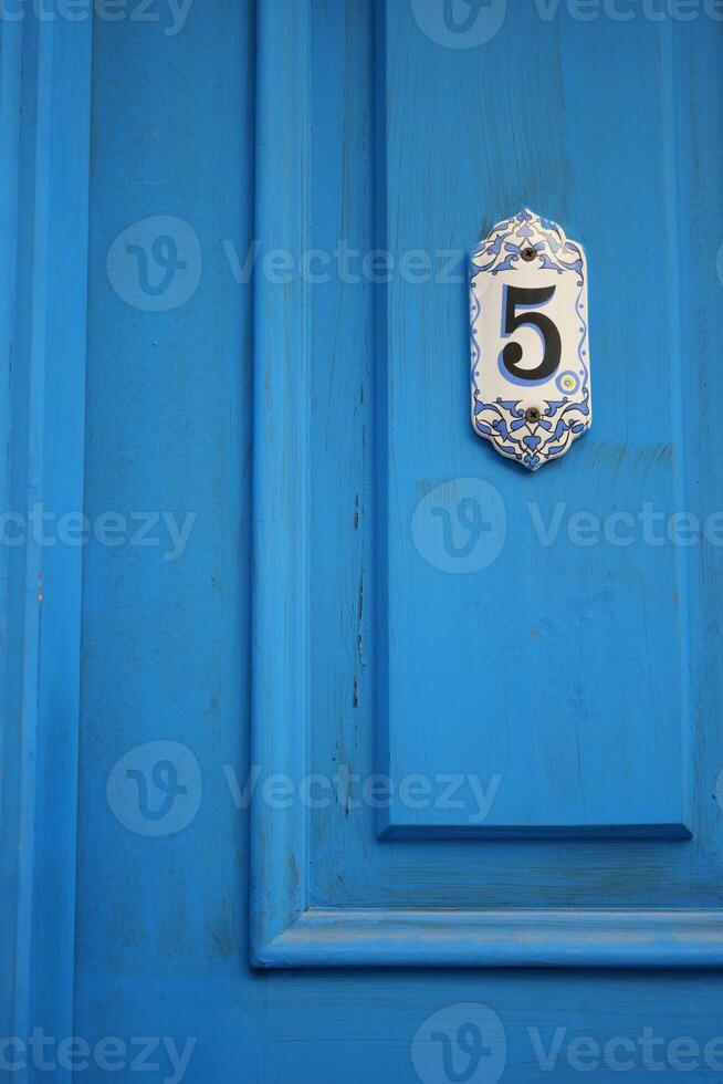 Bright blue door with number five displayed prominently photo