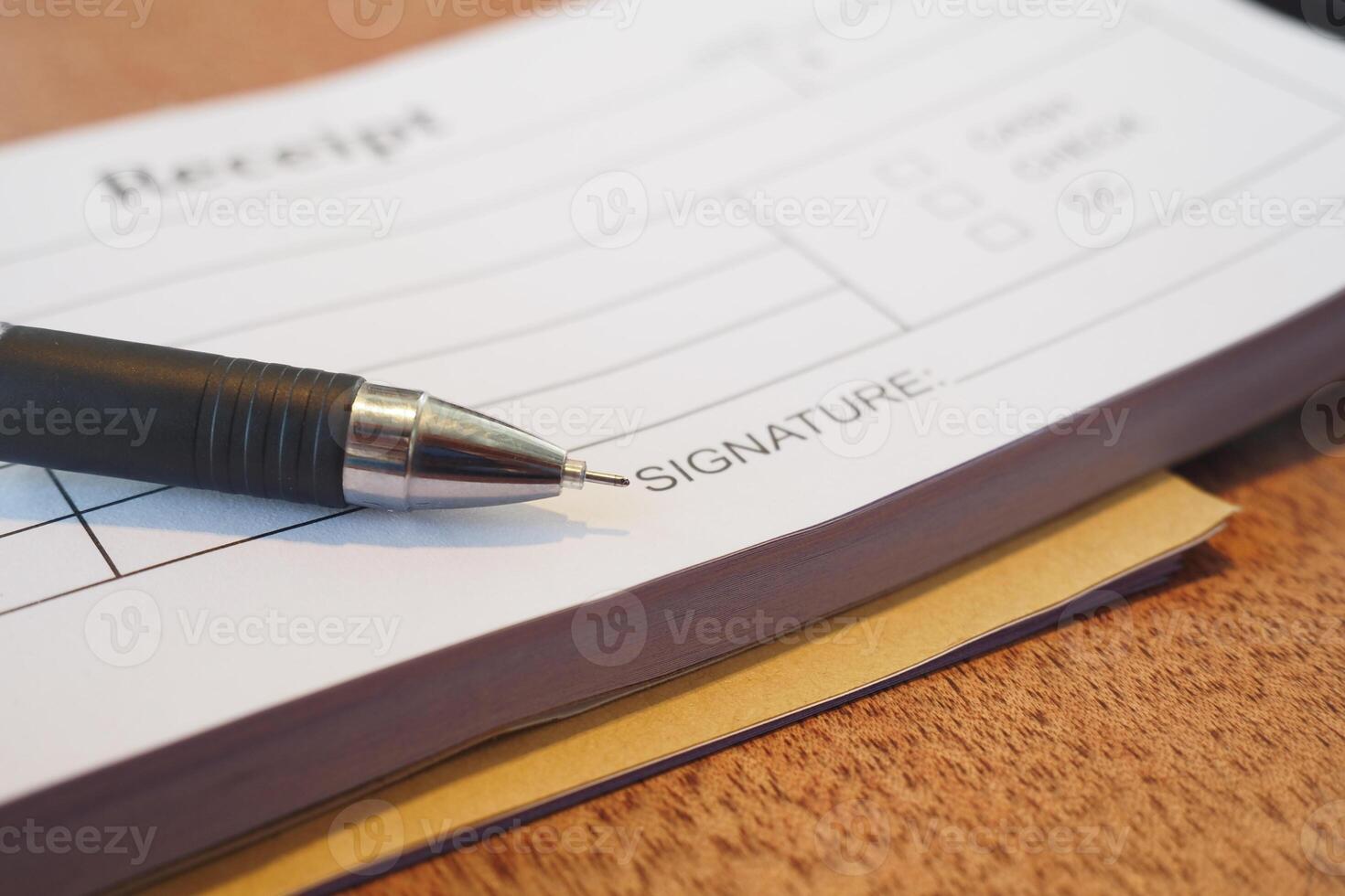 Receipt and pen lying on a wooden table during a transaction photo