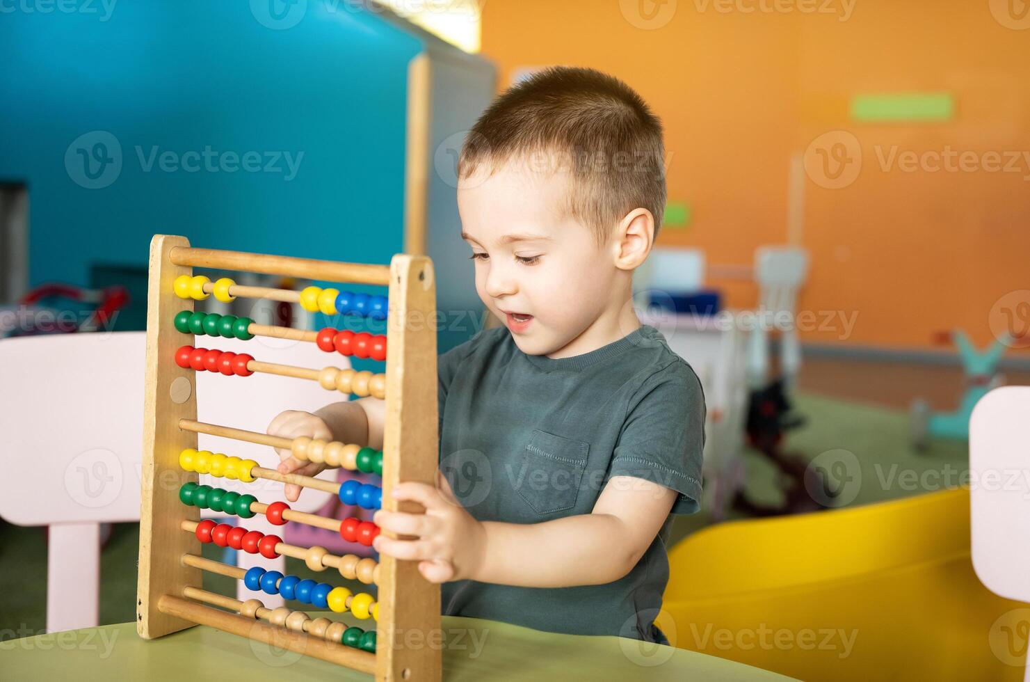Smiling toddler boy playing with colourful toy abacus in a children's entertainment center. Educational toys for children. photo
