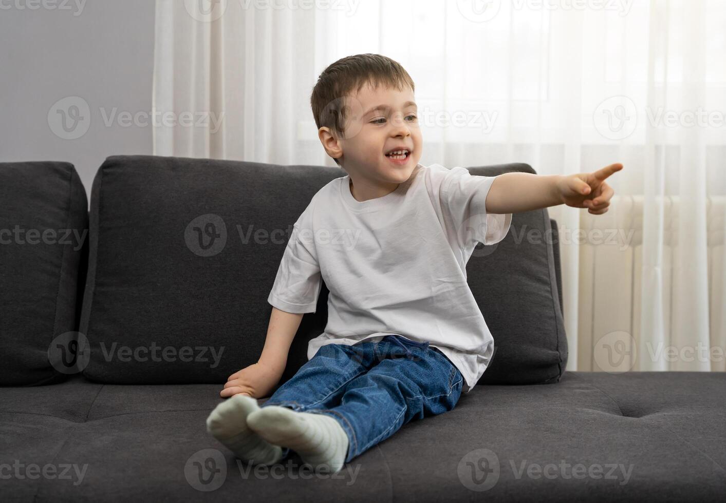 Little boy points his finger while sitting on the sofa. Interest, observation and learning new things. Observation skills, and early childhood curiosity. Developing cognitive skills, social engagement photo