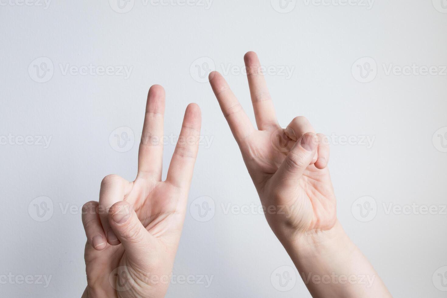 Caucasian hands displaying peace sign gestures against light background photo