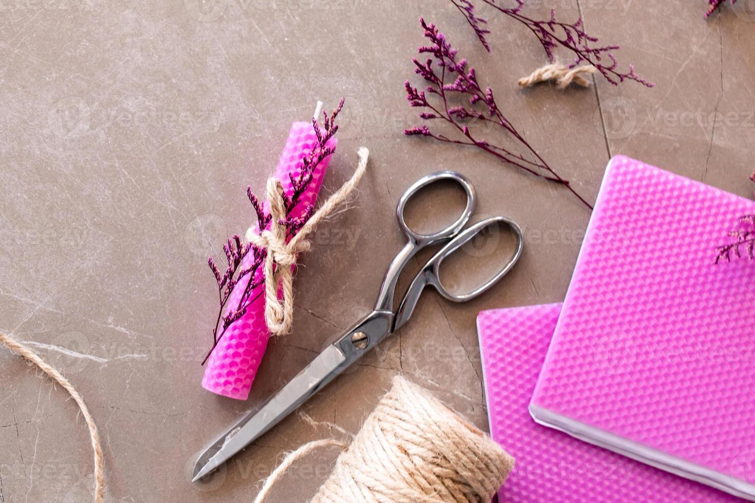 Crafting supplies with pink beeswax candles, scissors, and twine on brown surface photo