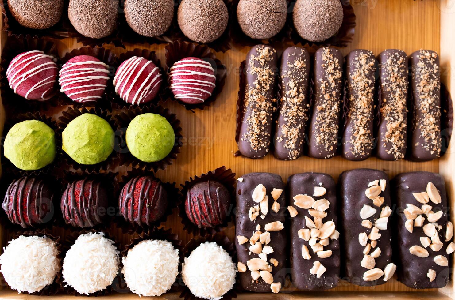 Assorted chocolate truffles and bars on a wooden tray with variety of toppings photo