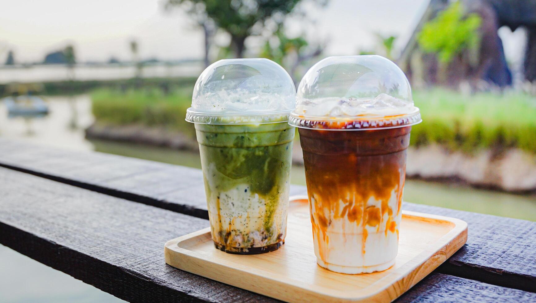 Close up and selective focus glass of ice matcha latte and ice coffee milk on wooden table. photo