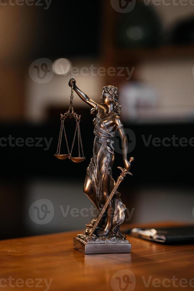 Lady justice statue is displayed on a wooden desk in a law office, symbolizing justice, fairness, and the legal system. Statue of Themis with a pair of scales of justice. Consulting a business client photo