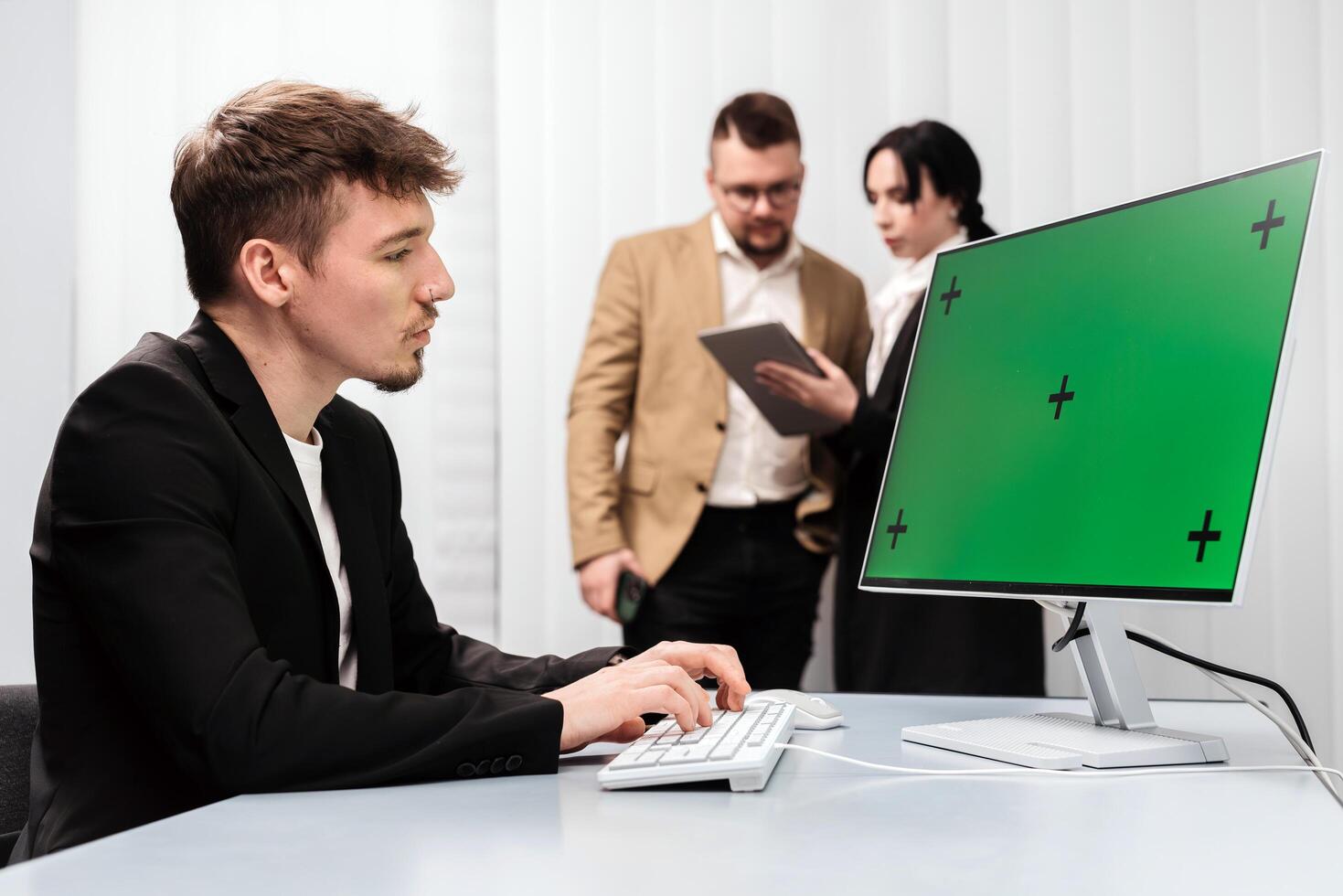 A group of successful businessmen in the office with a desktop computer featuring a Chroma Key green screen. Concept discussing deal completion, income growth, and strategic company development photo