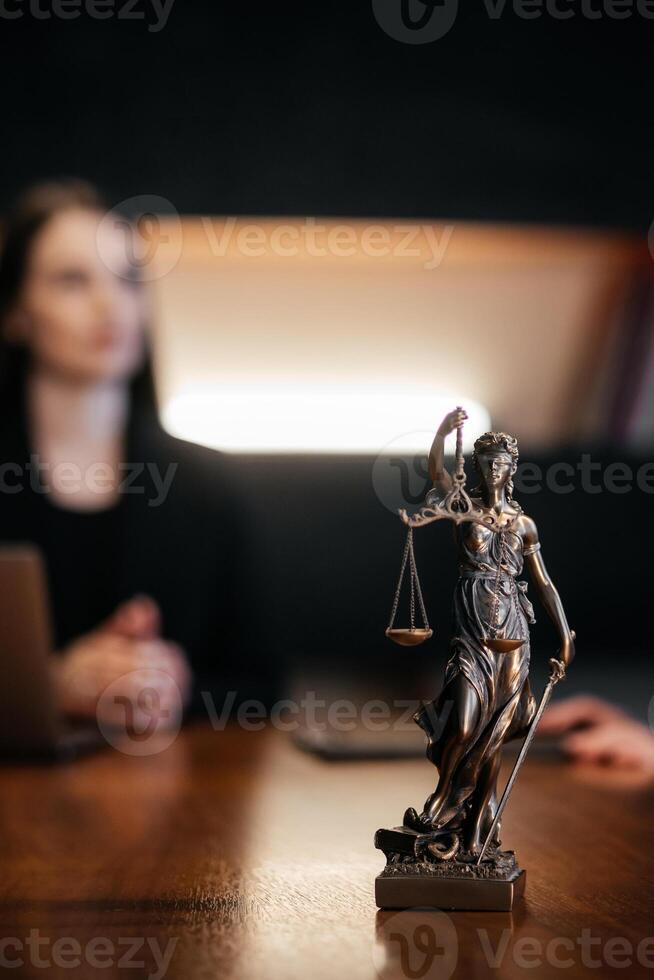 The Statue of Justice symbol on wooden table, legal law concept. Blurred Background. The scene suggests a serious and professional atmosphere. Vertical shot, selective focus photo