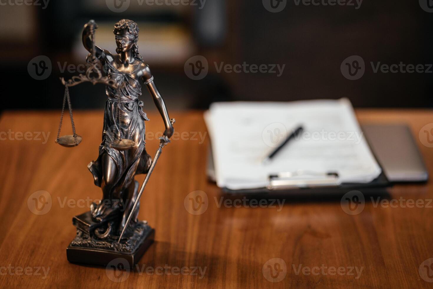 Golden lady justice statue is displayed on a wooden desk in a law office, symbolizing justice, fairness, and the legal system. Statue of Themis with a pair of scales of justice. Free copy space photo