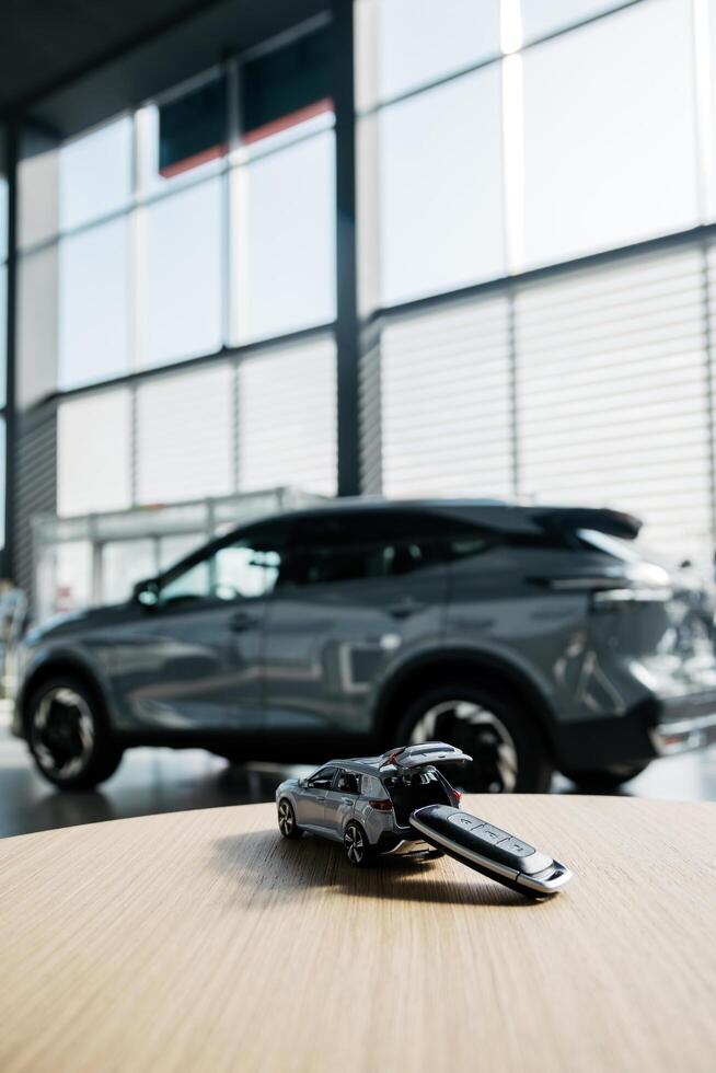 Tiny car model toy is placed on a table against dealership auto background. Premium car buying experience that combines expert guidance with high-class service in an elegant setting. Vertical shot photo