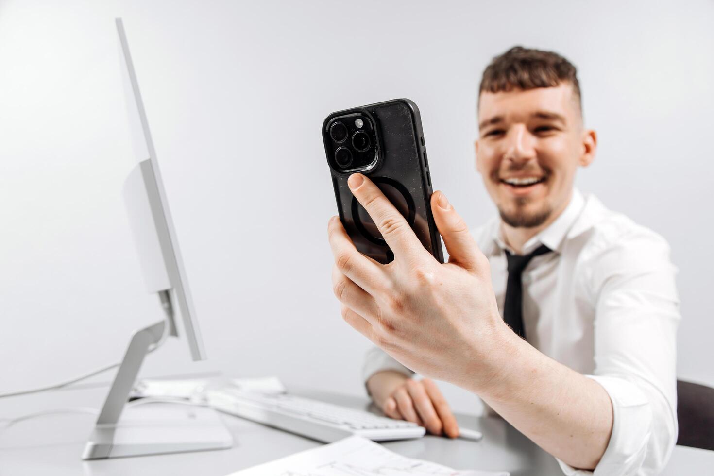 A business person receives a positive message on his phone while working at his computer. The concept of financial income, transaction photo