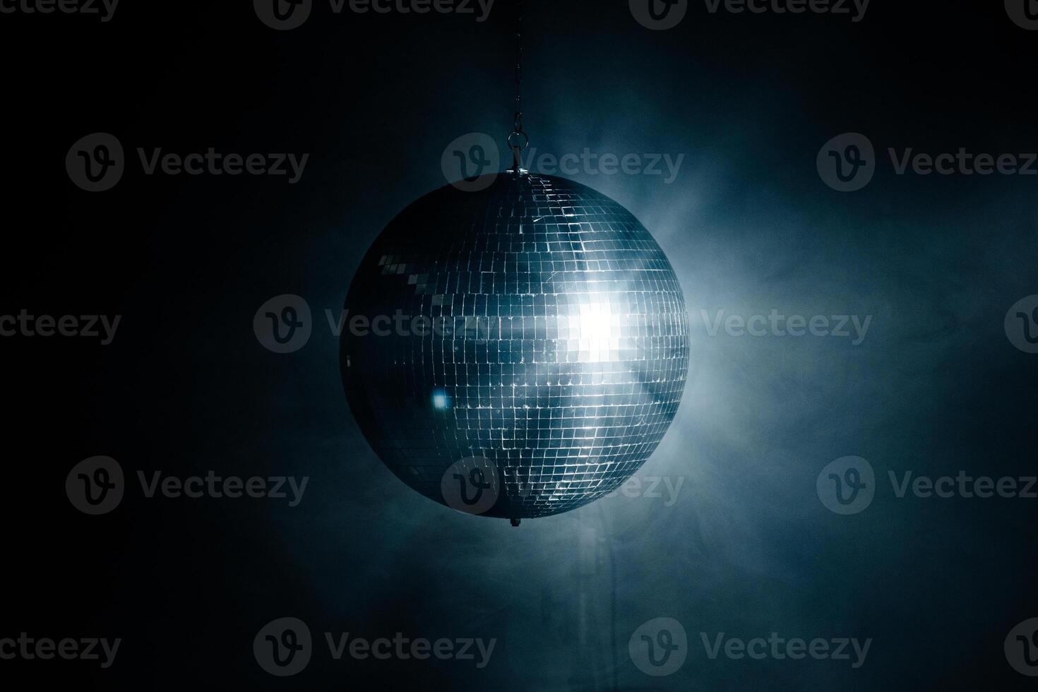 Close-up of a spinning disco ball reflecting dynamic rays of light against a black background. Perfect for creating a vibrant and energetic atmosphere at parties and events photo