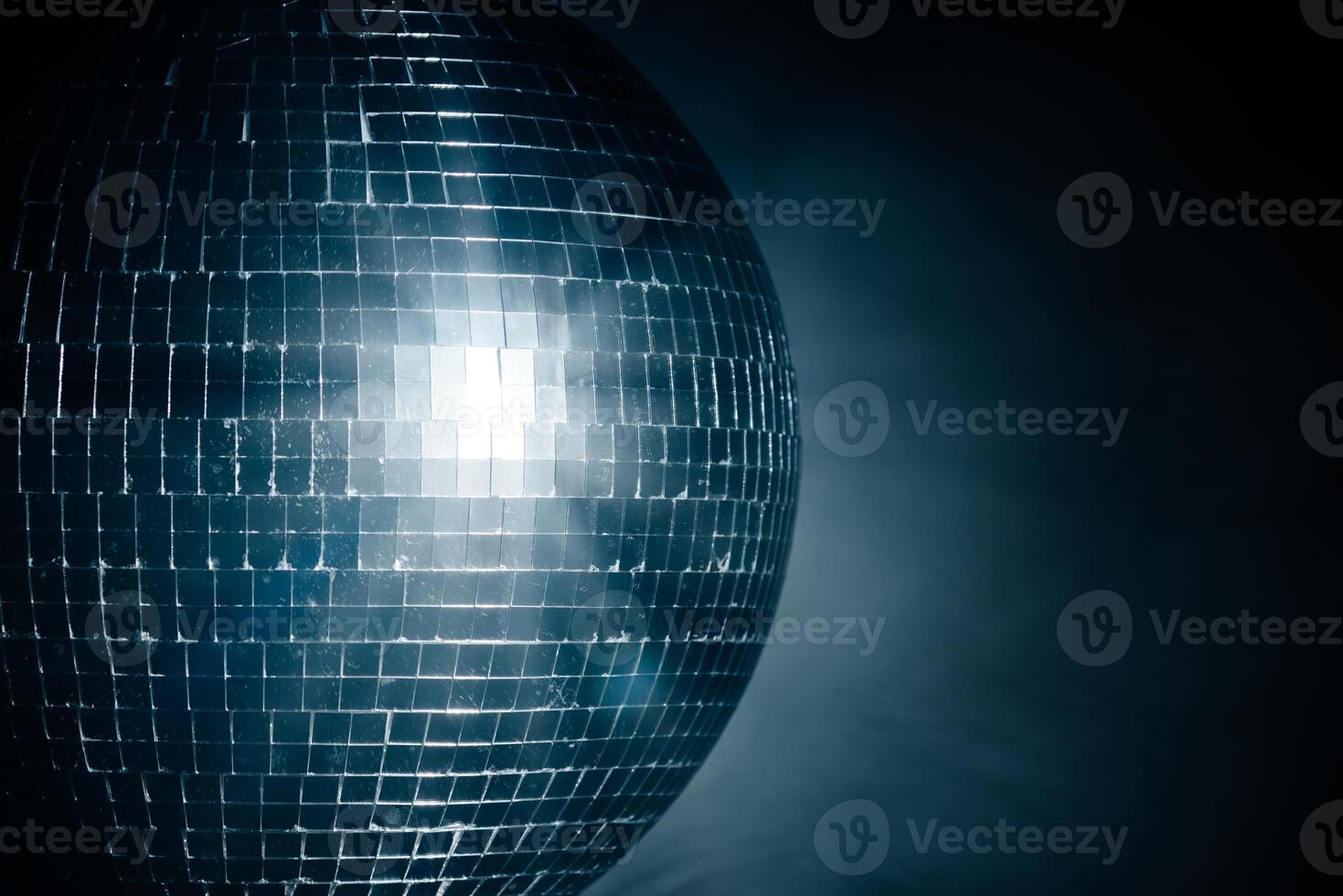 Close-up disco ball reflecting dynamic rays of light against a black background. Perfect for creating a vibrant and energetic atmosphere at parties and events photo