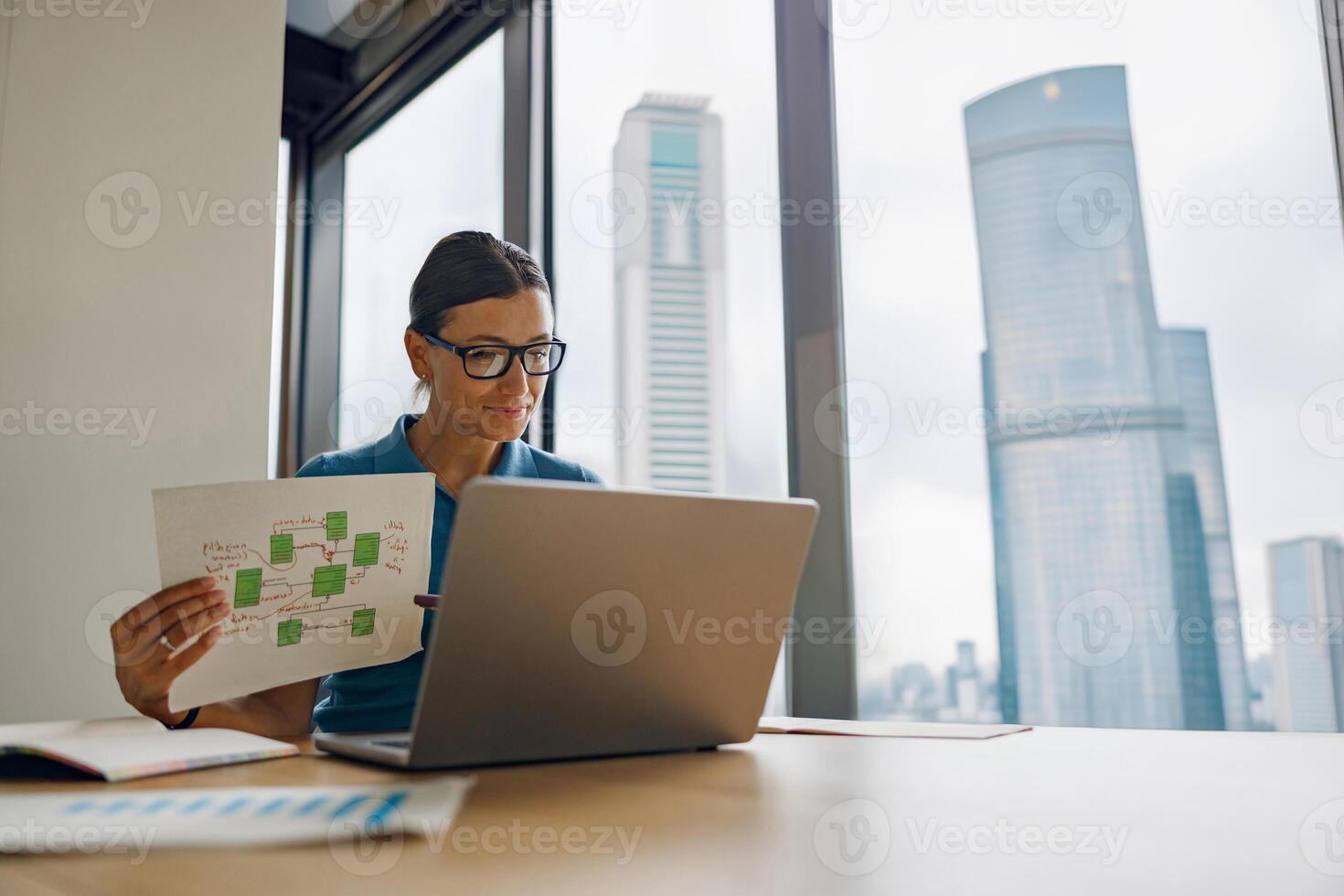 A professional analyzes data on a laptop with important documents in a corporate office photo