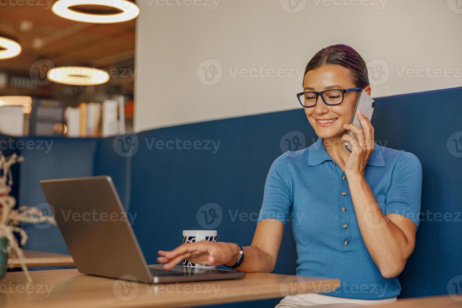 A businesswoman on a call while using her laptop in a modern workspace, showing efficiency photo