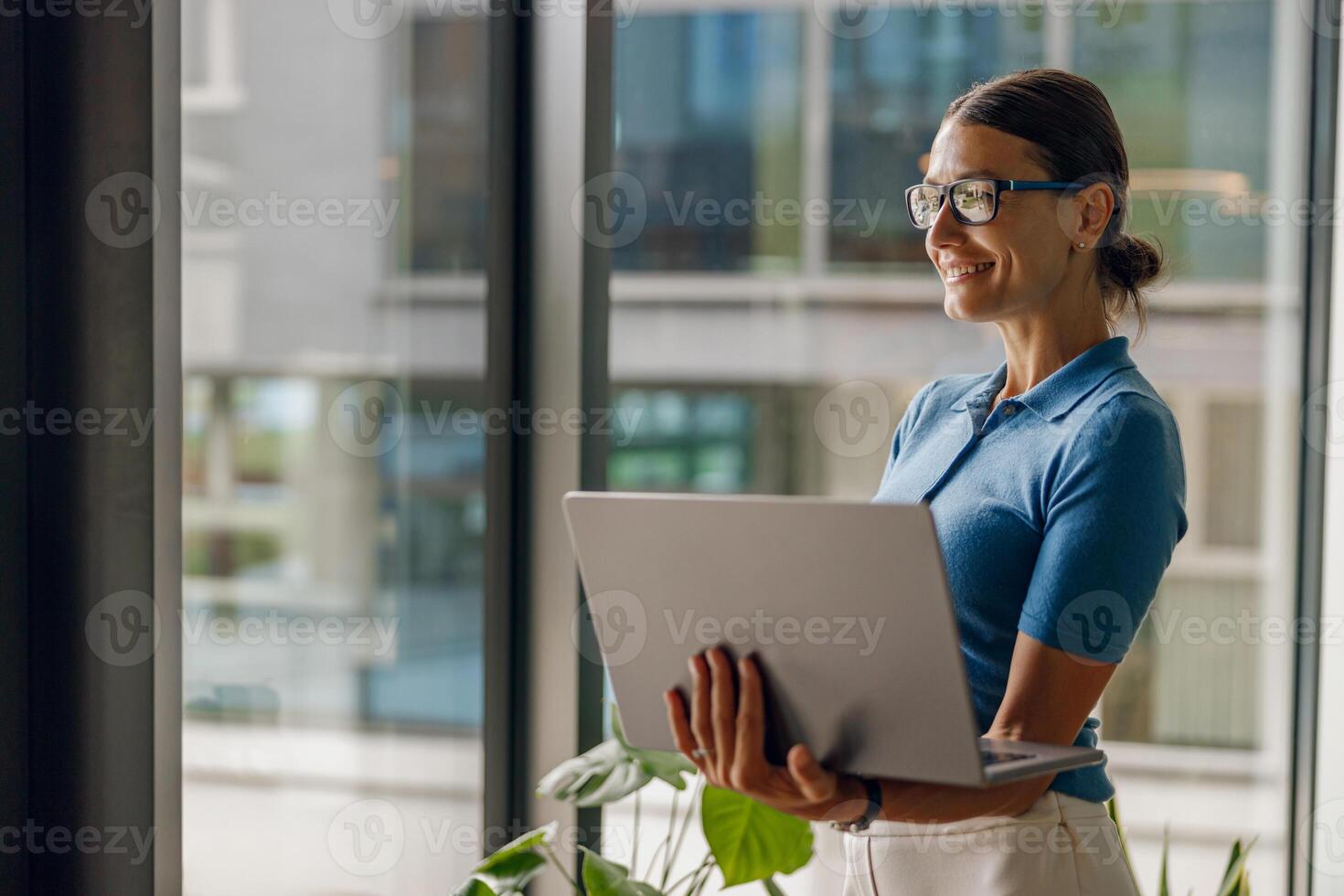A modern professional woman is diligently working with her laptop in a bright, open office space photo