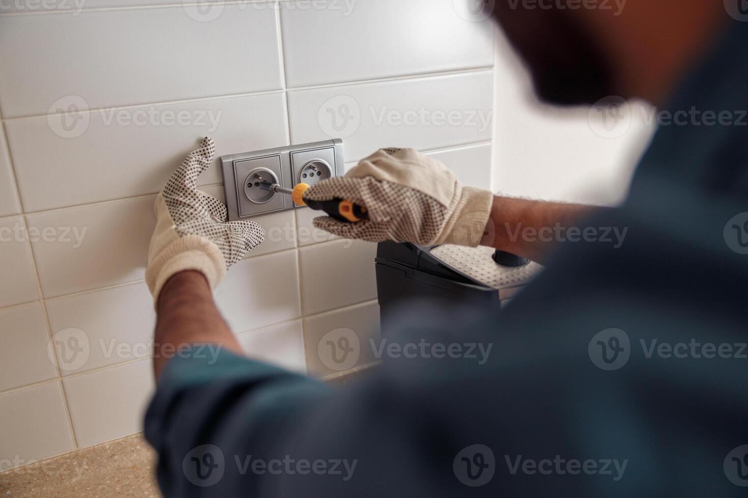 Close up of professional electrician worker with screwdriver is repairing power socket in kitchen photo