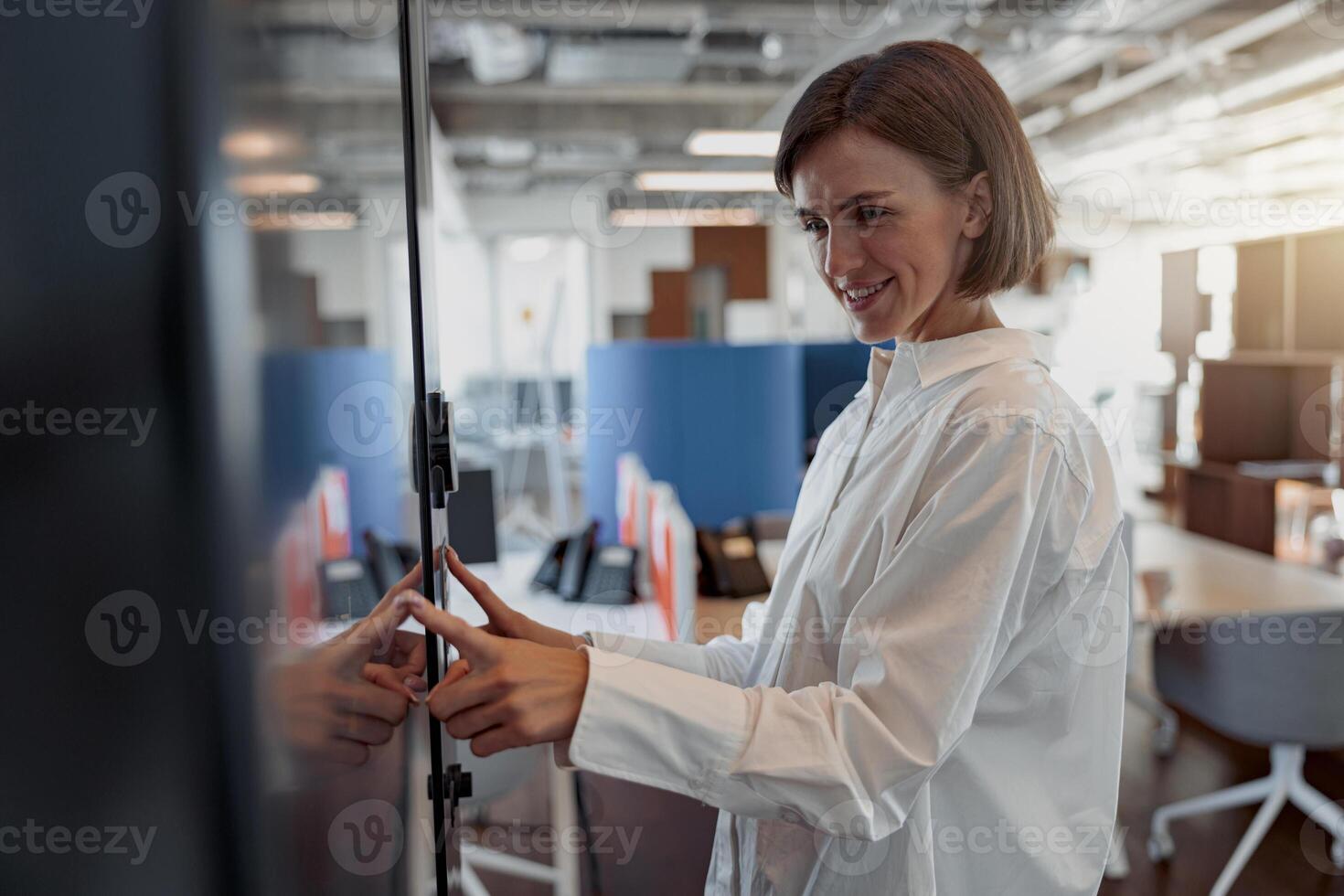 Smiling woman entering password or PIN code to unlock and access the security door at office photo