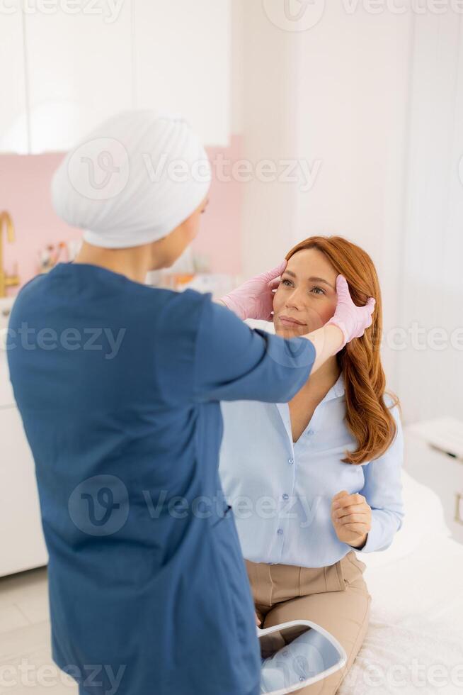 A woman getting her face checked by a doctor photo