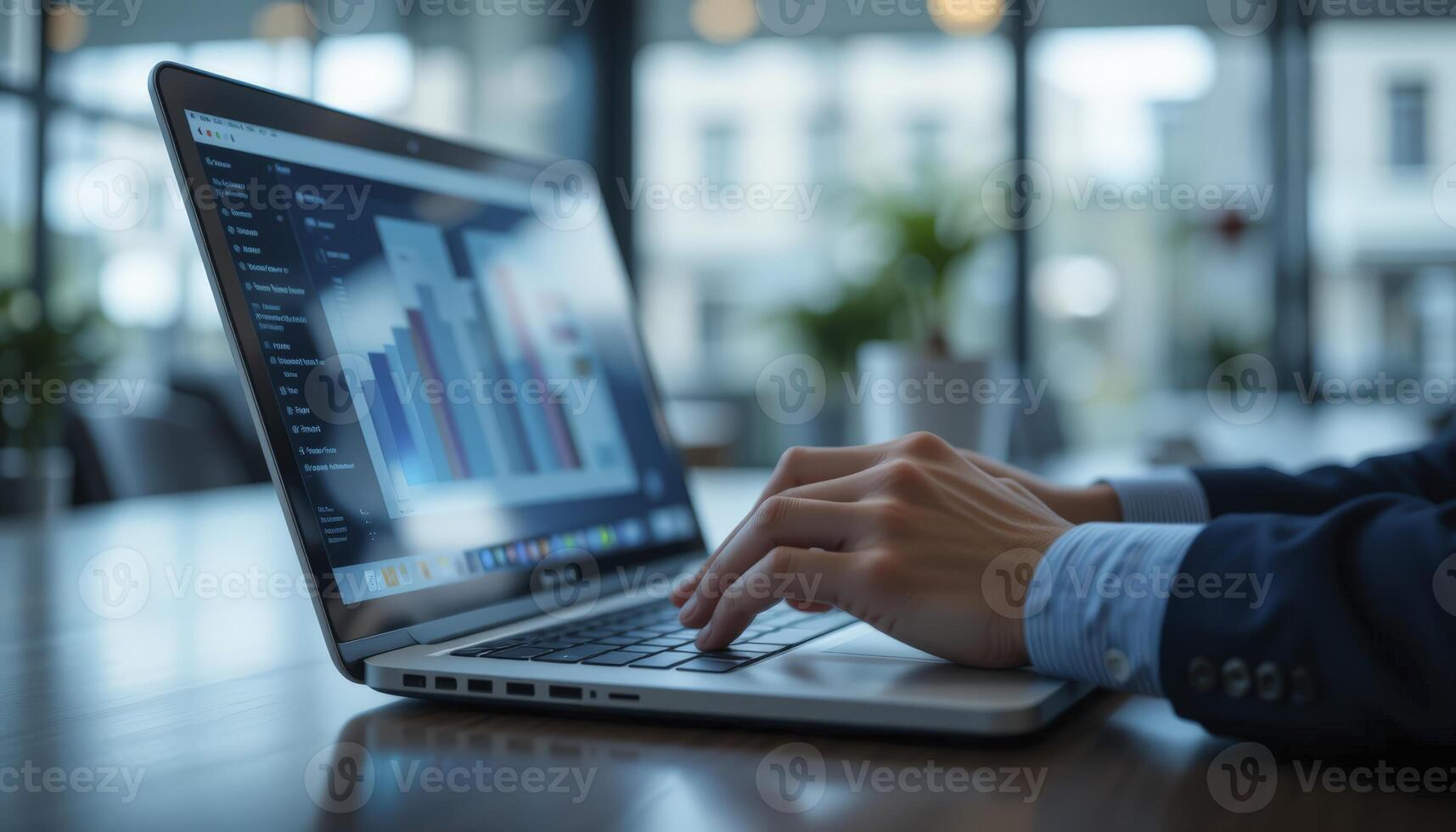 Person Typing on Laptop with Data Graphs in Modern Office photo