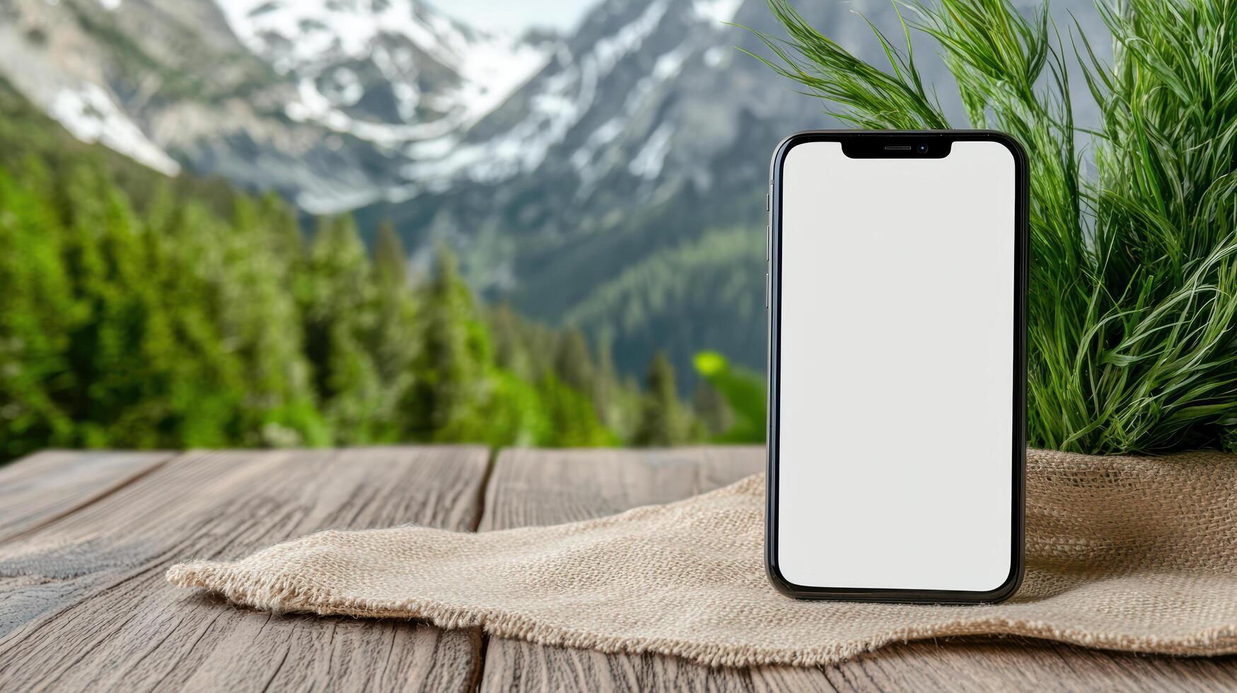 A smartphone with blank screen on a wooden table with mountains in the background photo