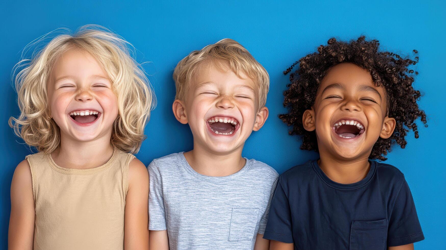 Three children laughing and smiling on a blue background photo