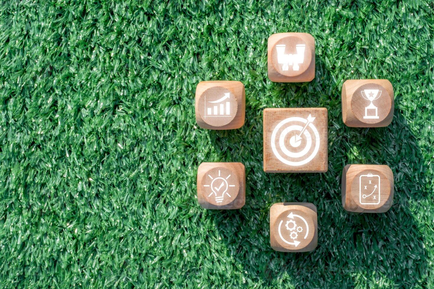 Wooden blocks with strategy icons on grass, symbolizing business planning, innovation, and success. photo