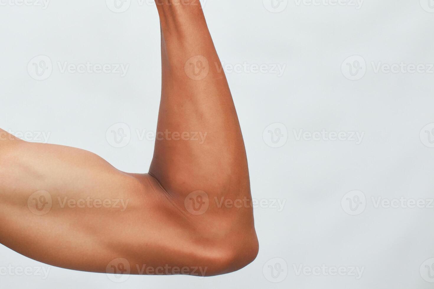 Closeup Of A Flexed Muscular Arm With Brown Skin Against A Light Background photo