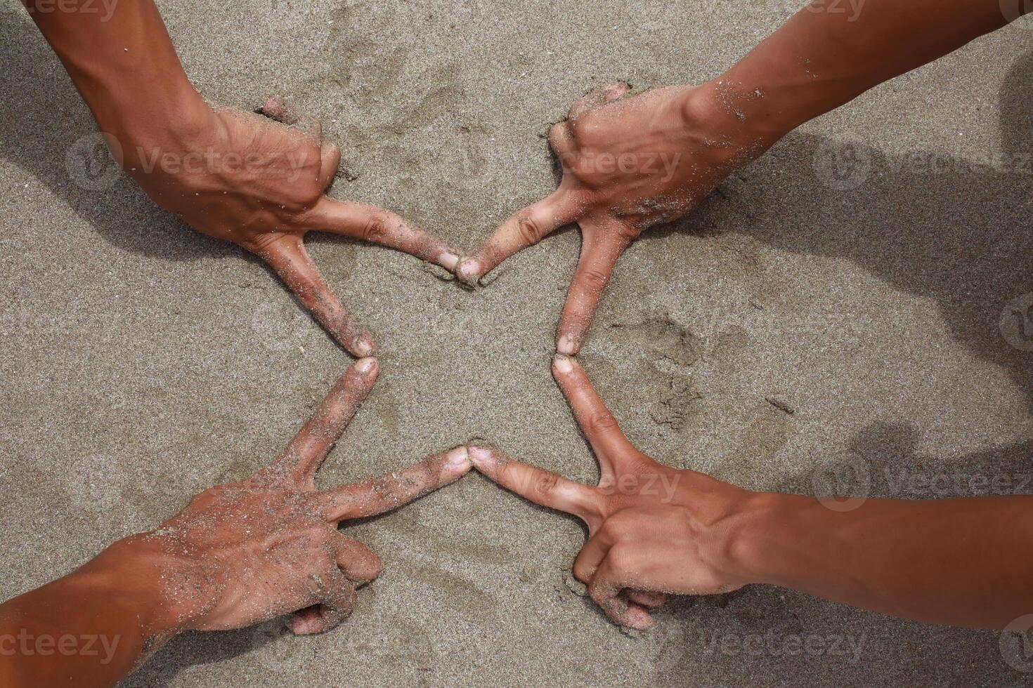 Hands Forming a Star Shape on Sand, Coastal Unity and Collaboration photo