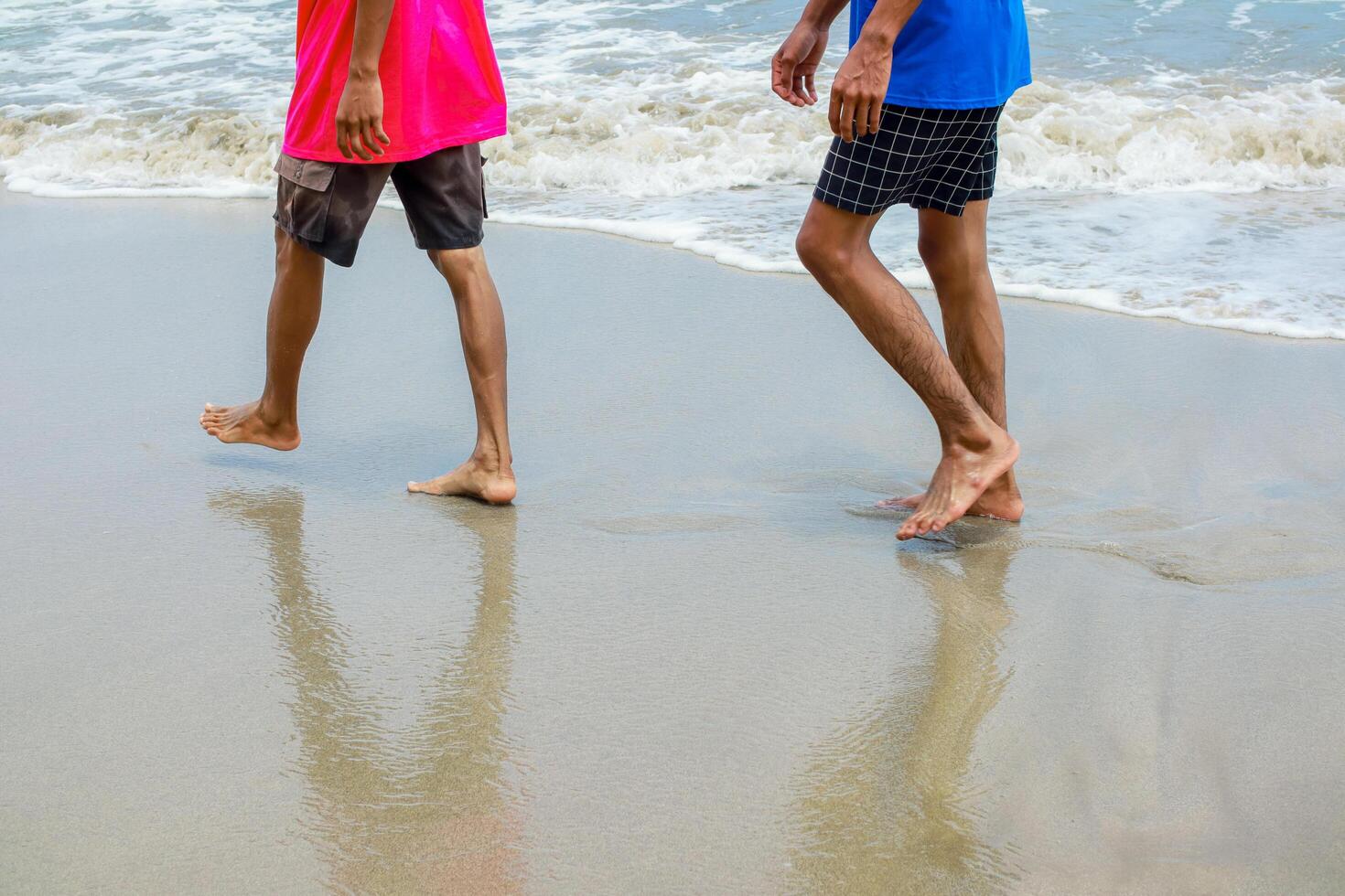 Two Individuals Walking on a Sandy Beach Along the Shoreline photo