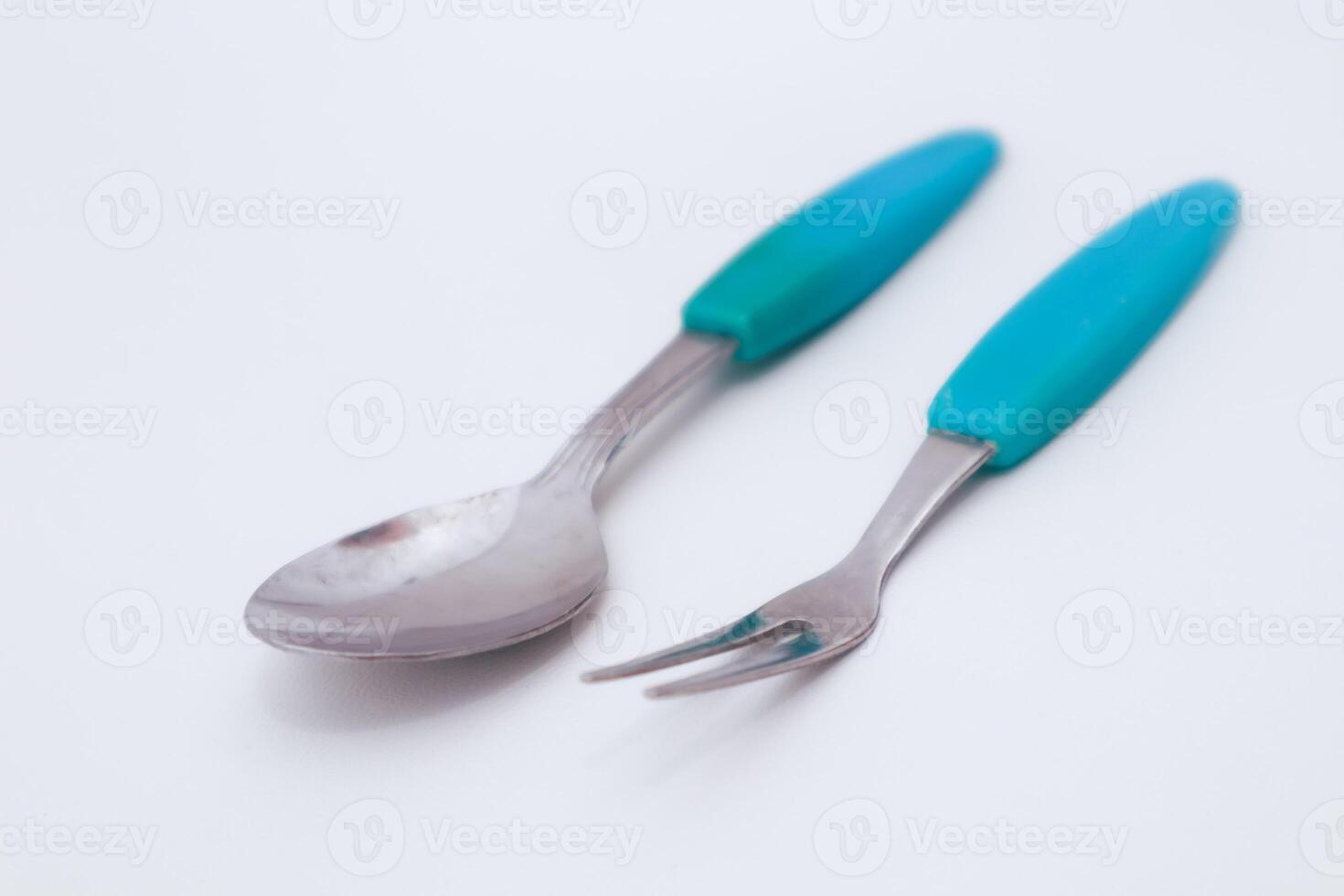 Spoon and Fork Utensils in Turquoise Handle Placed on a White Surface photo