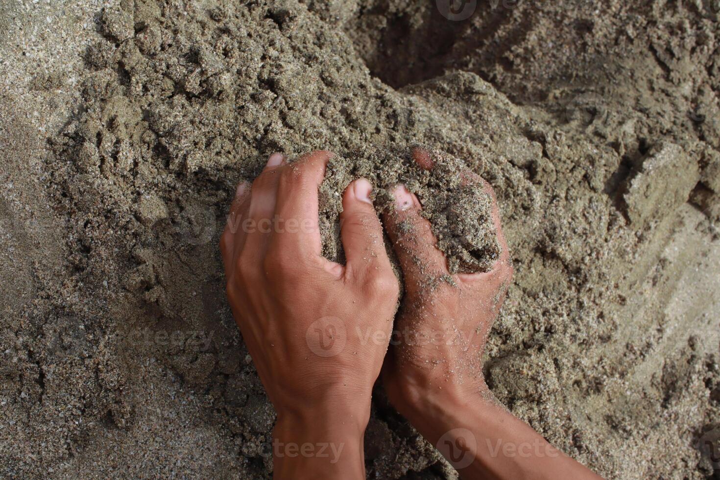 Hands holding a handful of sand, feeling the granular texture and nature's raw material photo