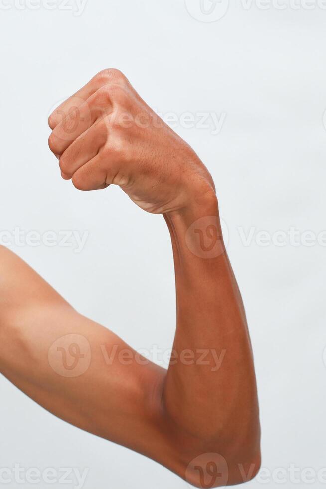 Close Up Of A Flexed Male Arm With Brown Skin Against A Light Background Showing Muscle Definition photo