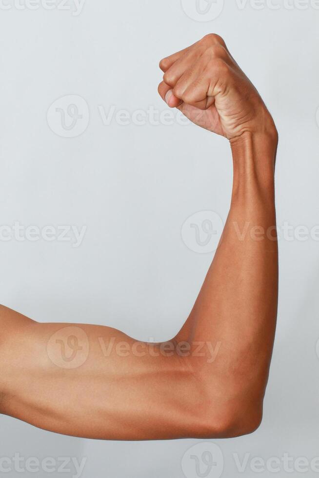 Closeup Of A Flexed Arm Against A Light Gray Background Showing Muscle Definition And Toned Skin photo
