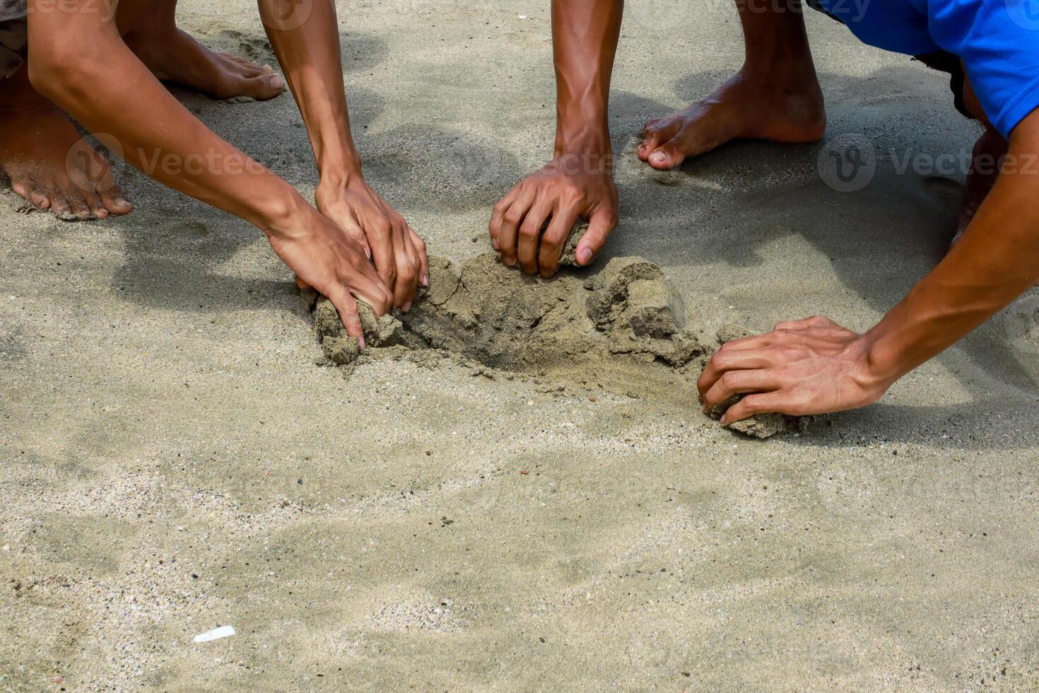 Collaborative sand sculpting on a bright beach, hands shaping the sculpture photo