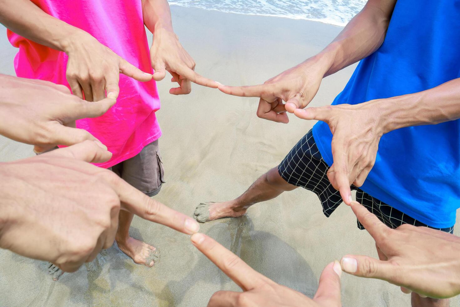 A Group of People Pointing at a Central Point on the Beach photo