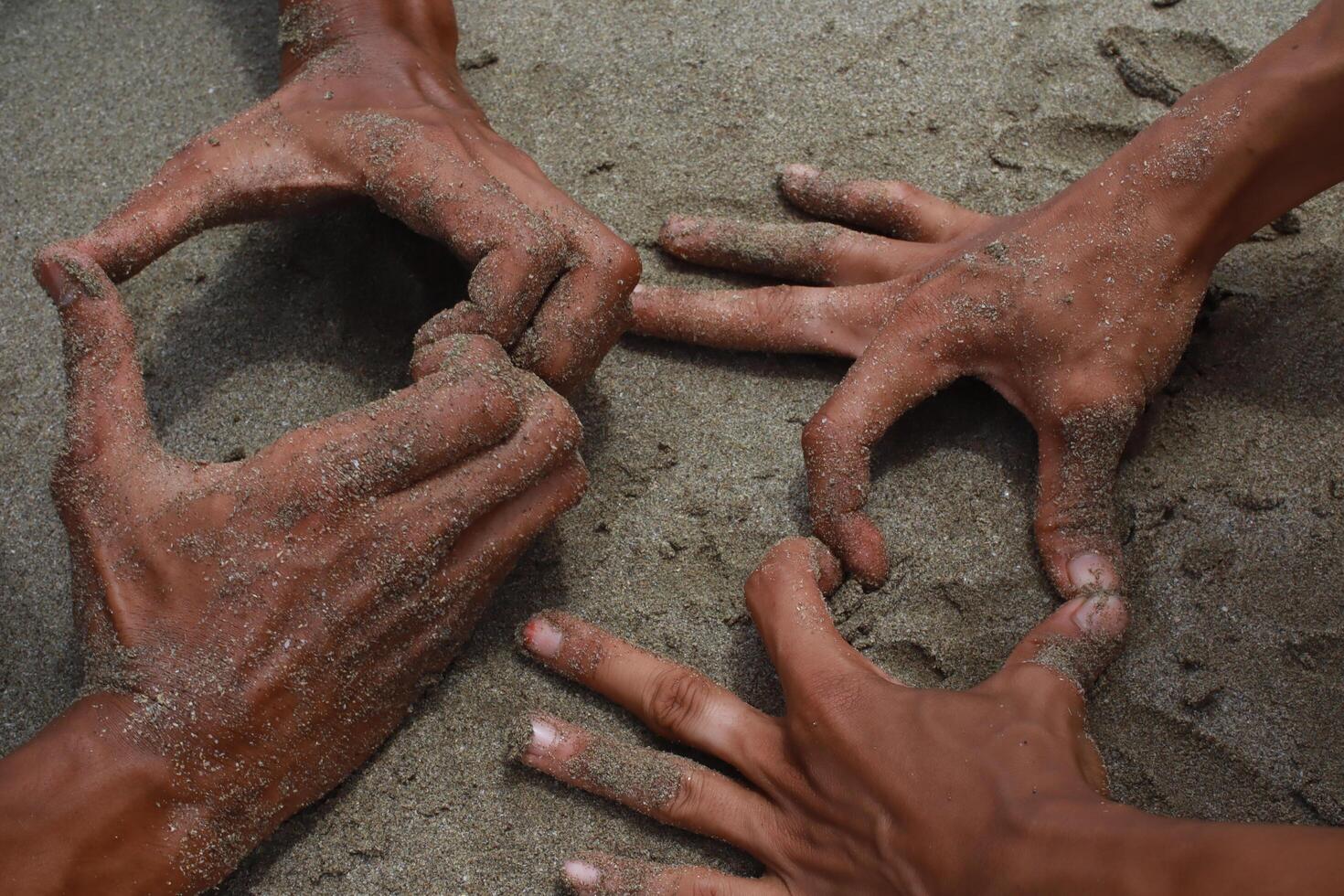 Hands Covered in Sand Creating Geometric Shapes on a Beach Surface photo