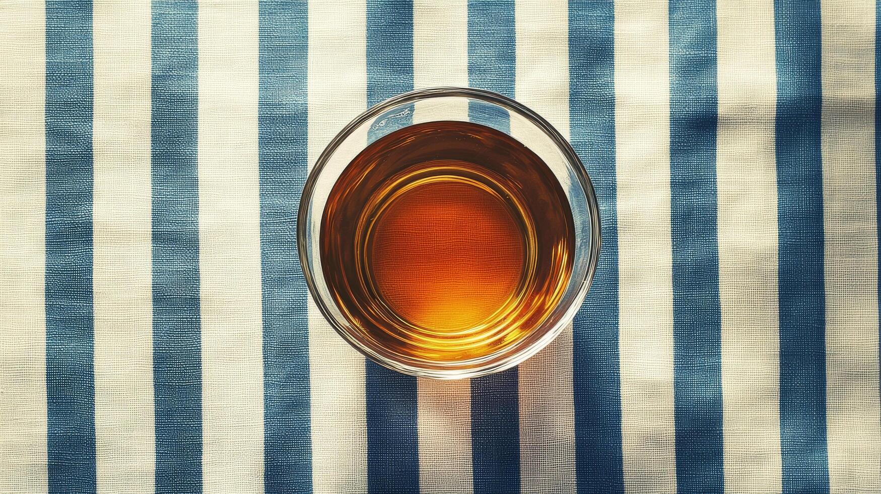 A glass of whiskey on a blue and white striped tablecloth photo