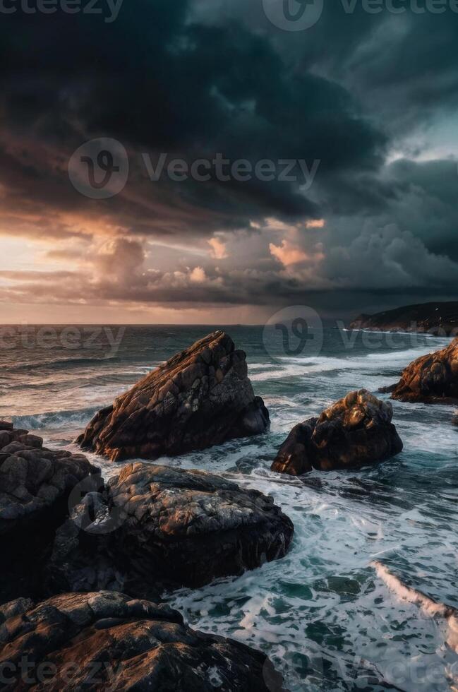 A stormy sunset over the ocean with rocks and water photo