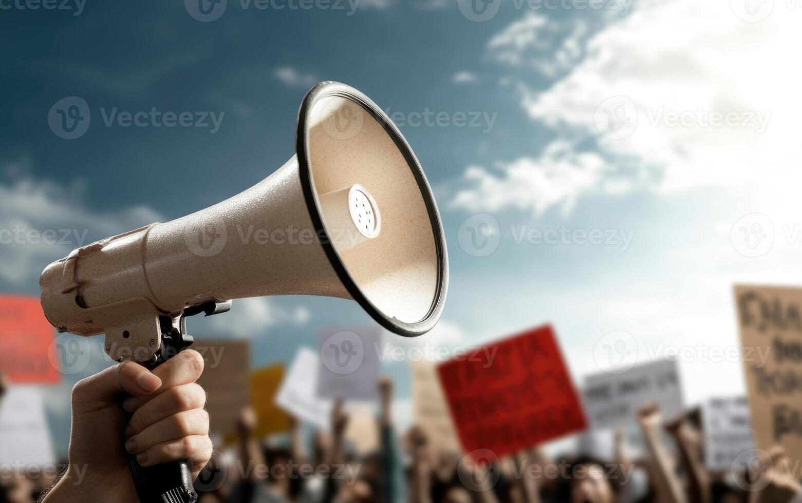 A megaphone is held up in front of a crowd of people holding up signs photo