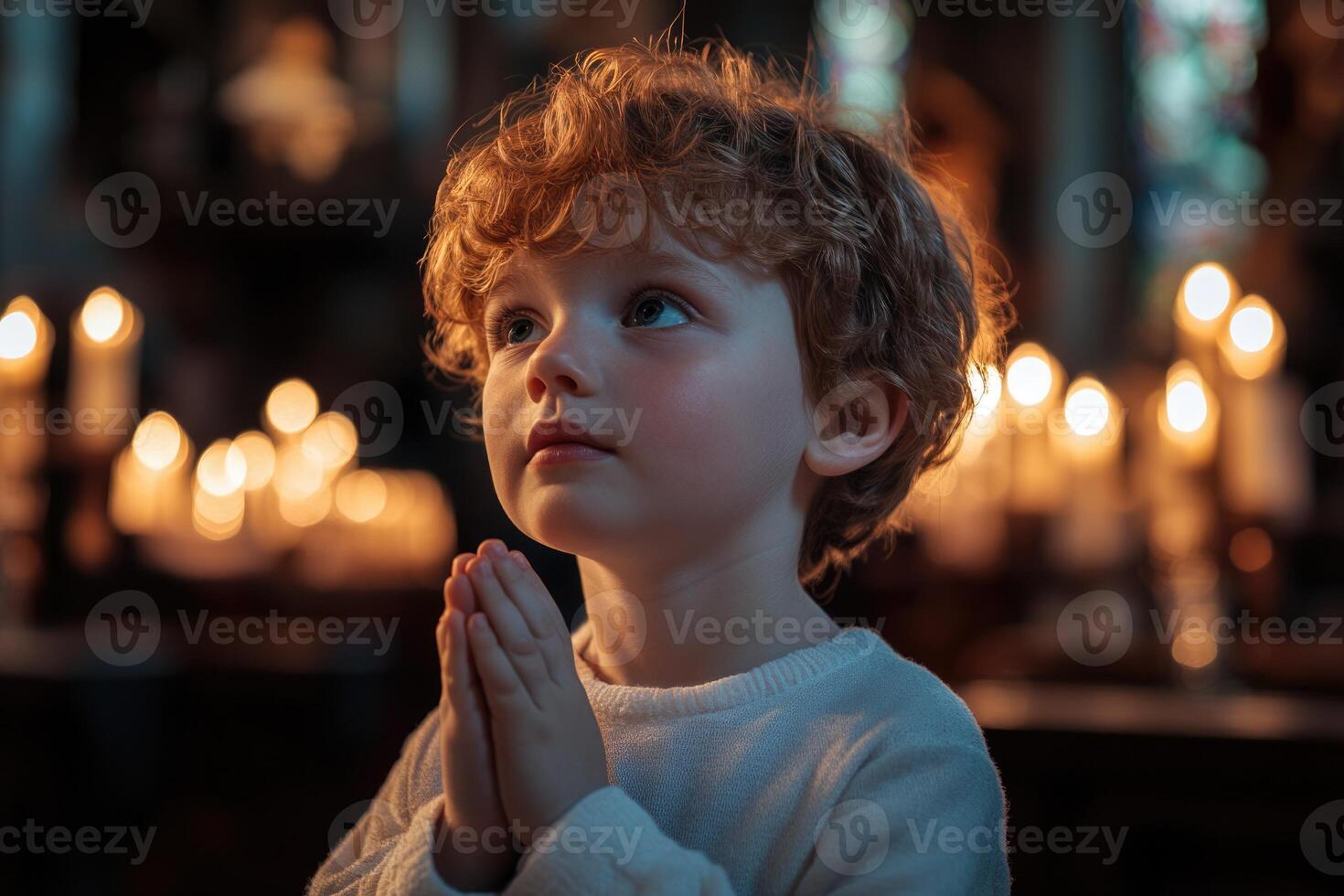 A young boy is praying in front of candles photo