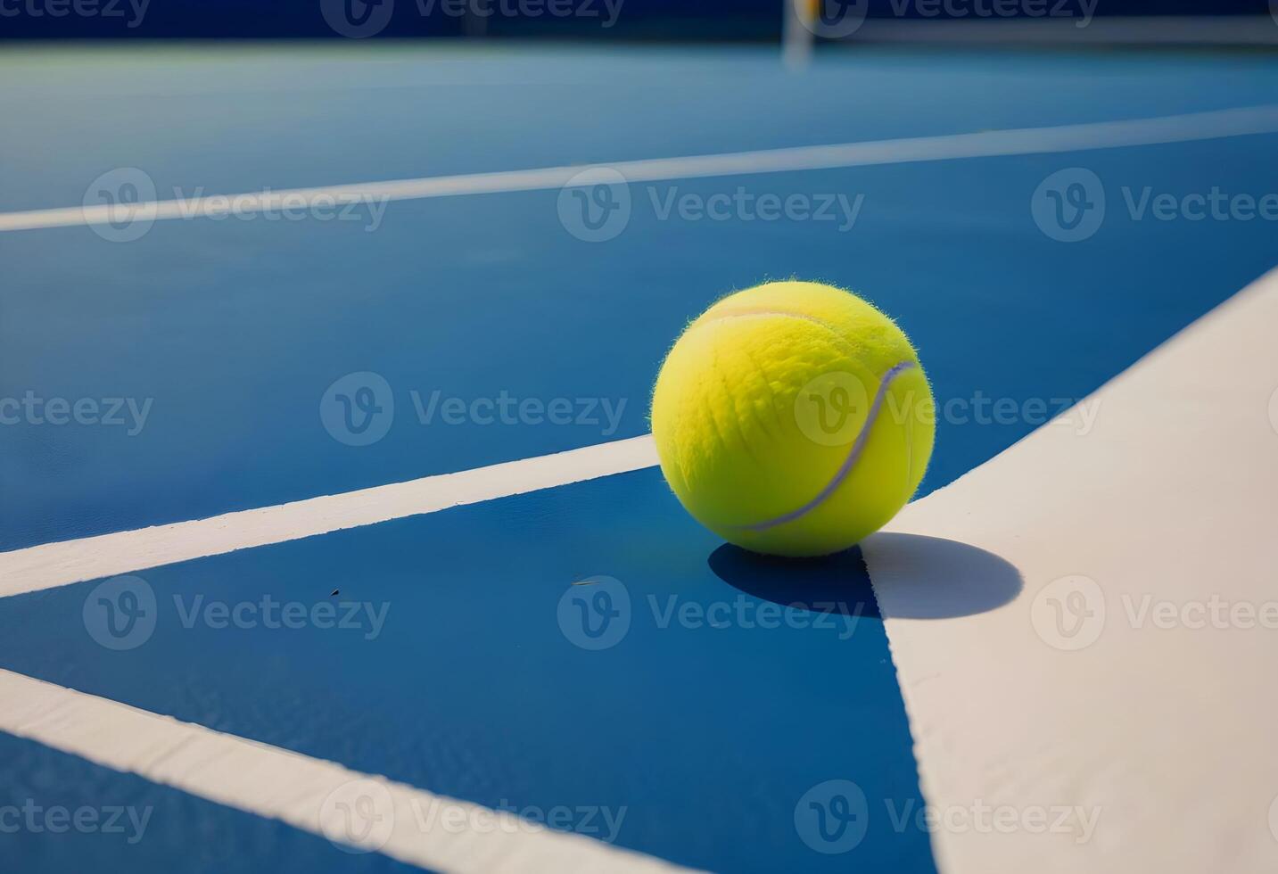 A tennis ball resting on the intersection of a blue and white line on a tennis court. photo