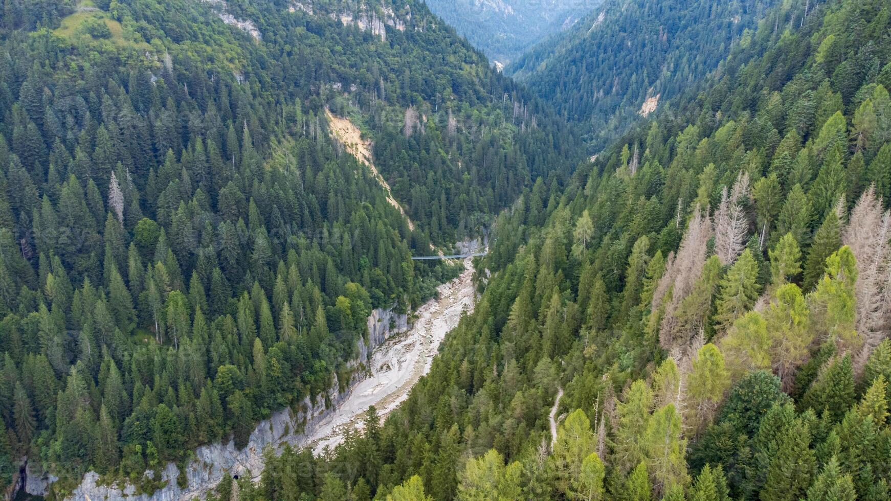 Tibetan bridge in a canyon in the middle of nature. Aerial view of a suspended rope bridge in Noana Valley in Trentino photo