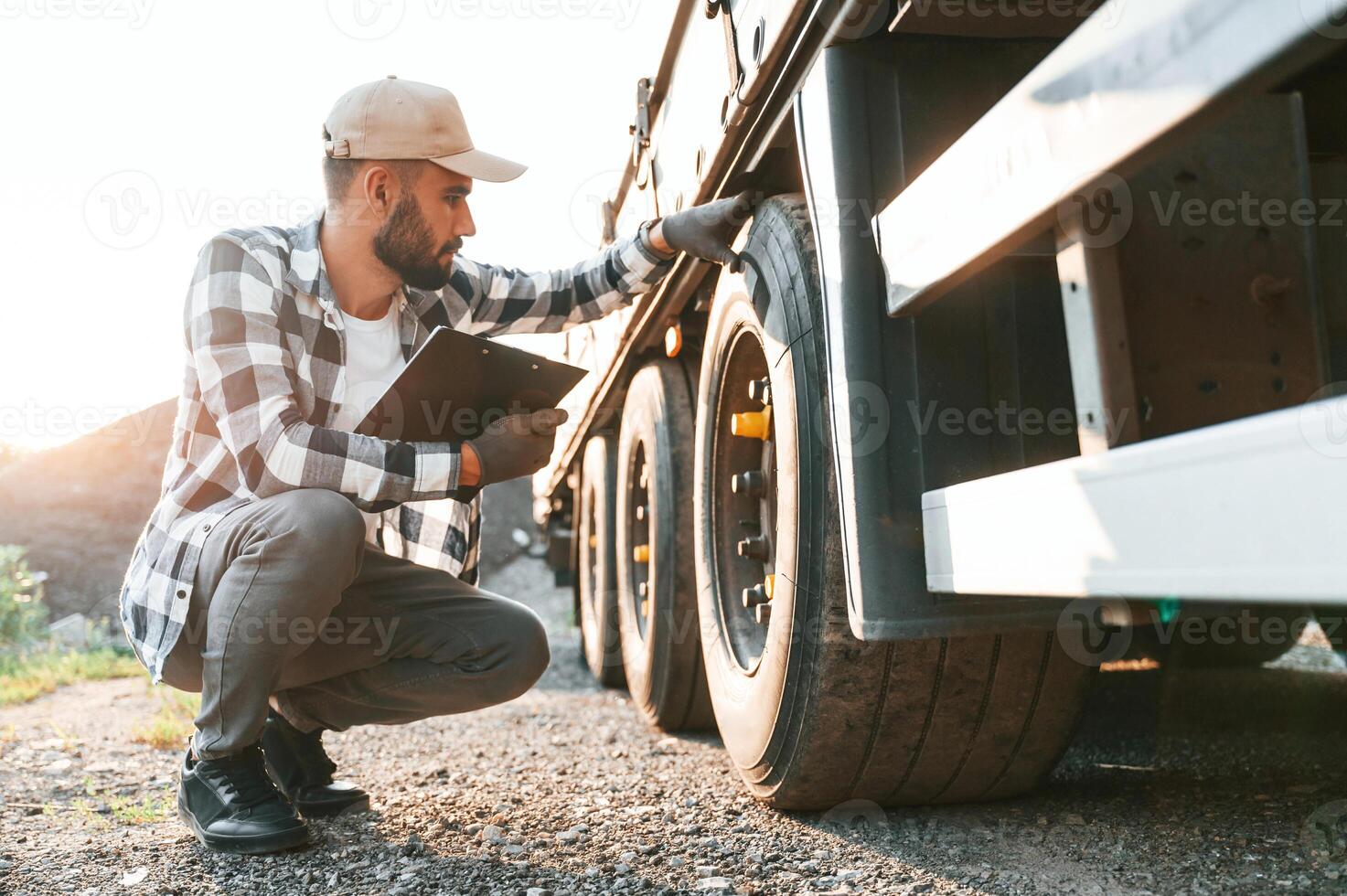 Working with wheels.. Young truck, driver is with his vehicle at daytime photo