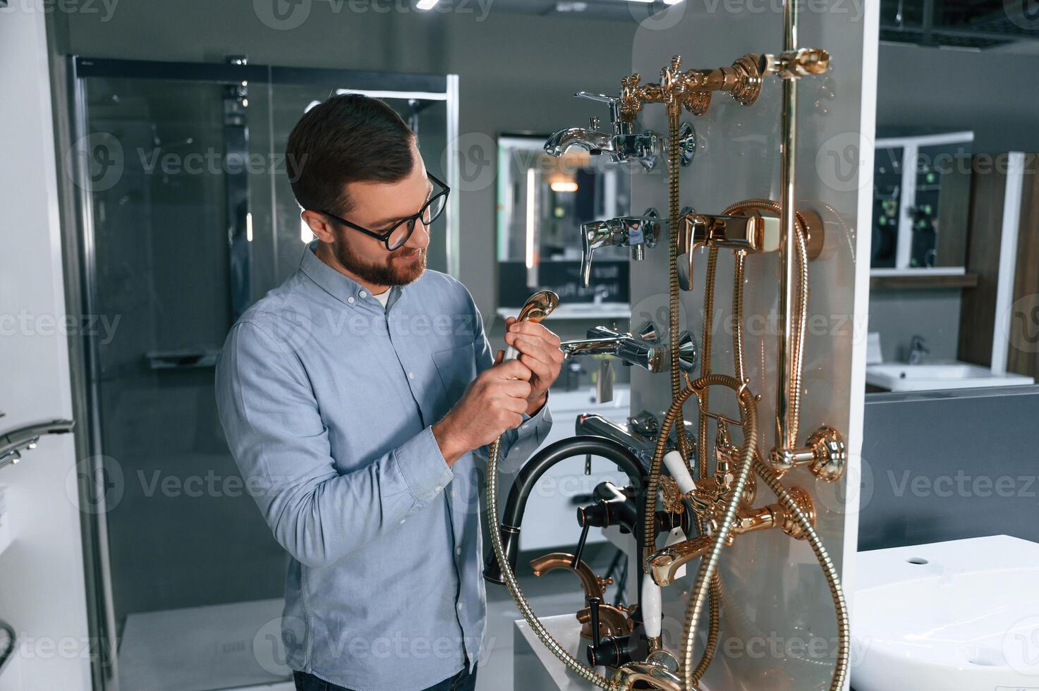 Selects,a shower faucet.. Man chooses a products in a sanitary ware store photo